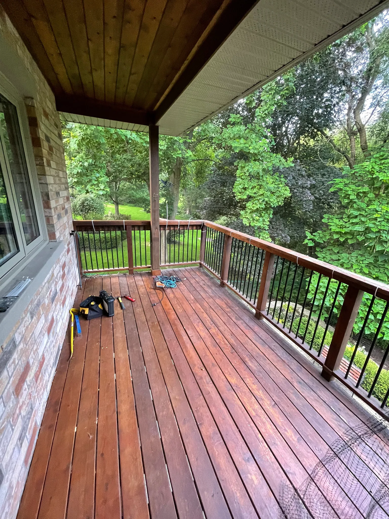 Covered wood deck with stained boards and wood railing