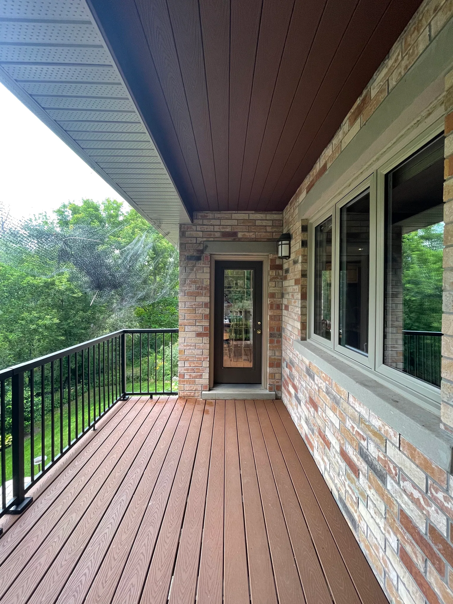 Composite deck boards and black railing beside the back door