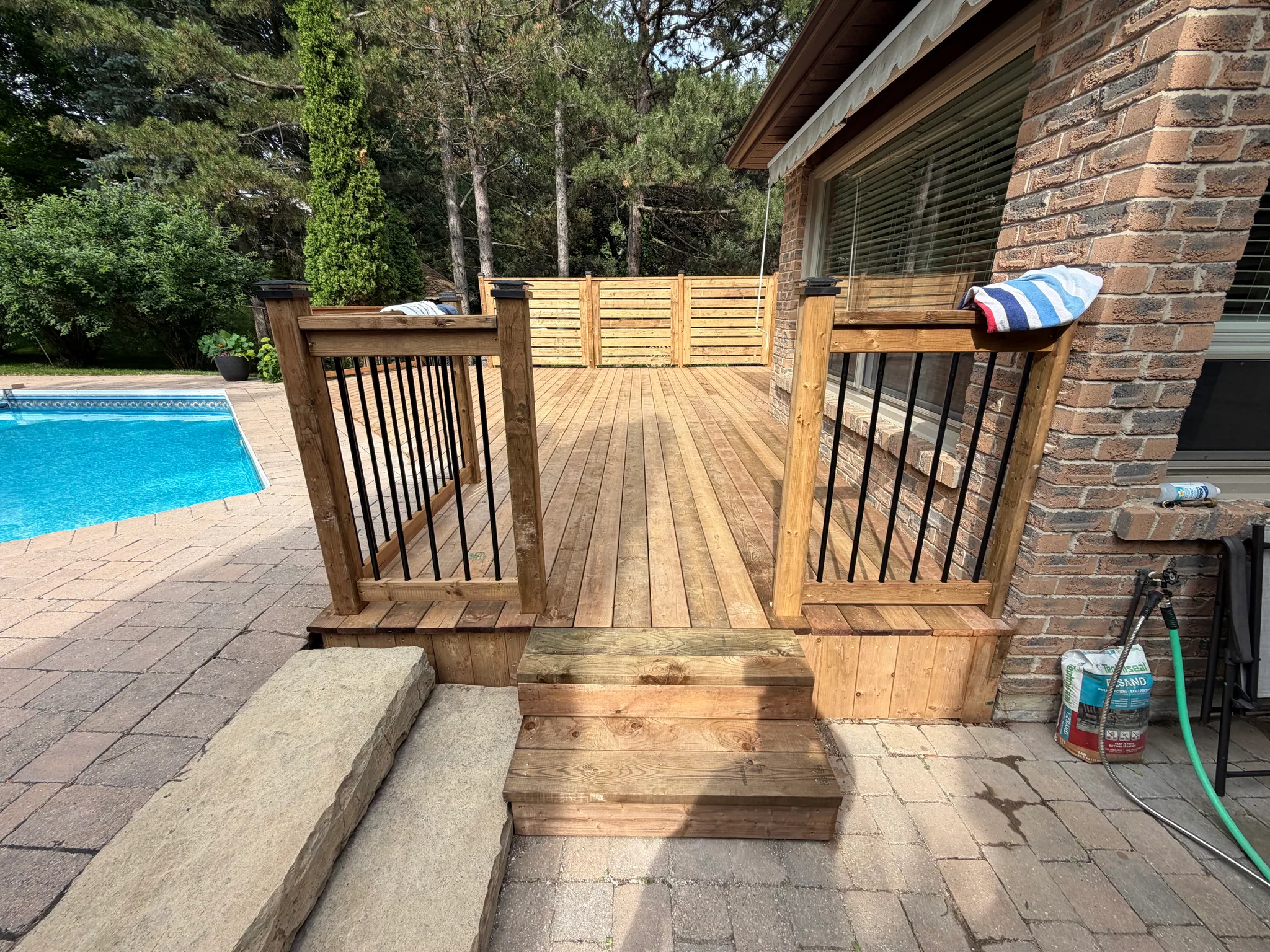 Poolside wood deck with new steps and black railing