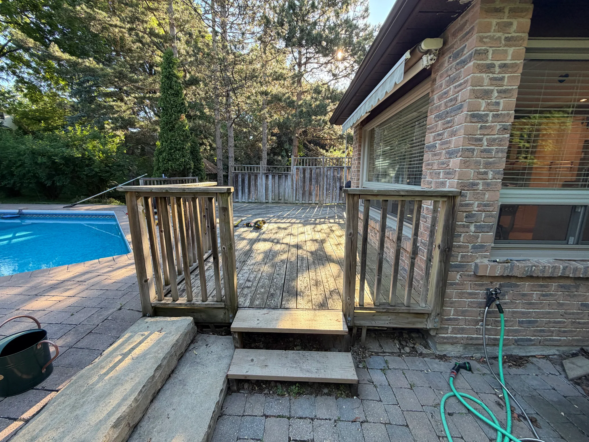 Worn poolside deck with old wood steps and railing