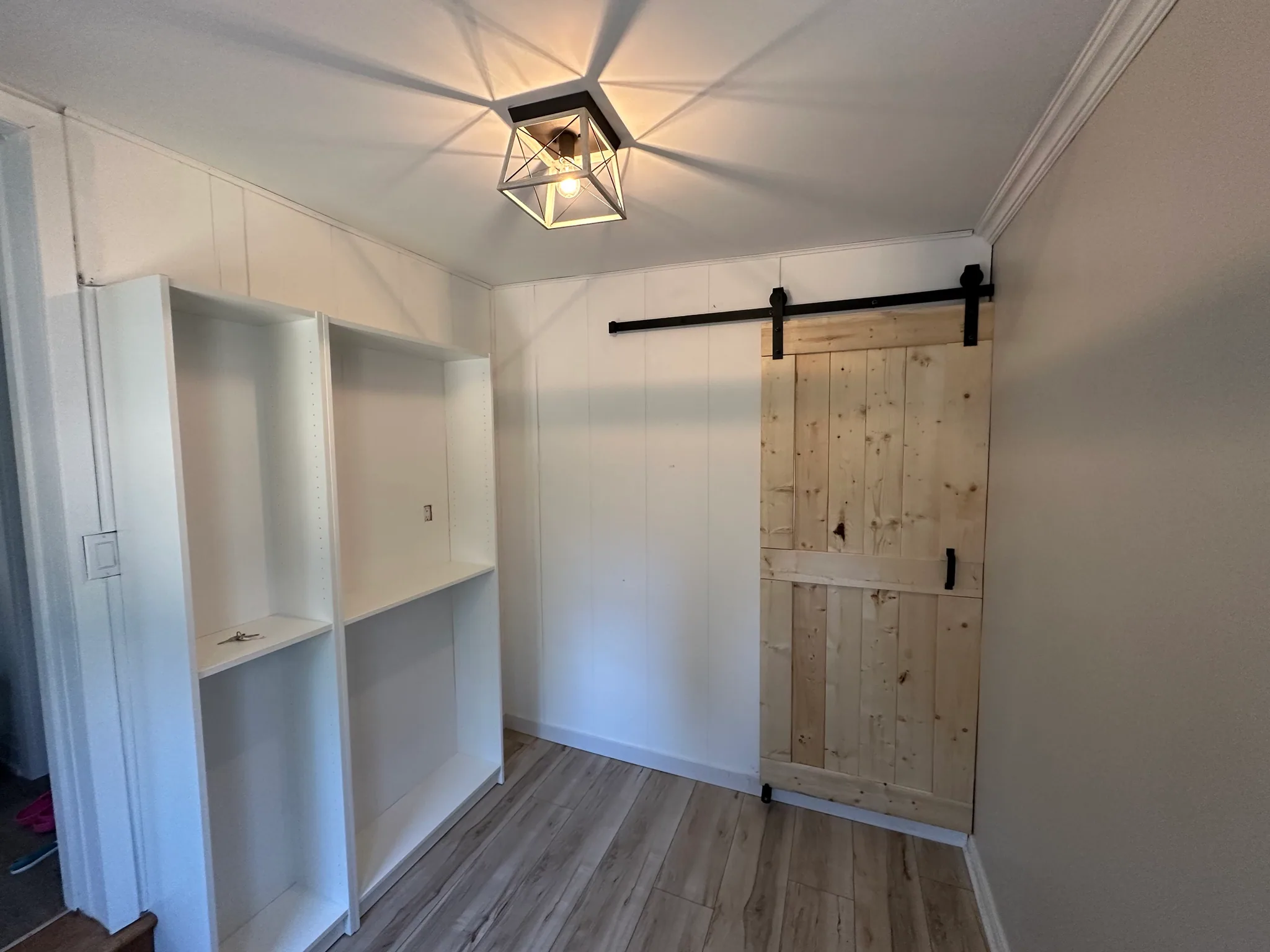 Sliding wood door beside built-in shelves