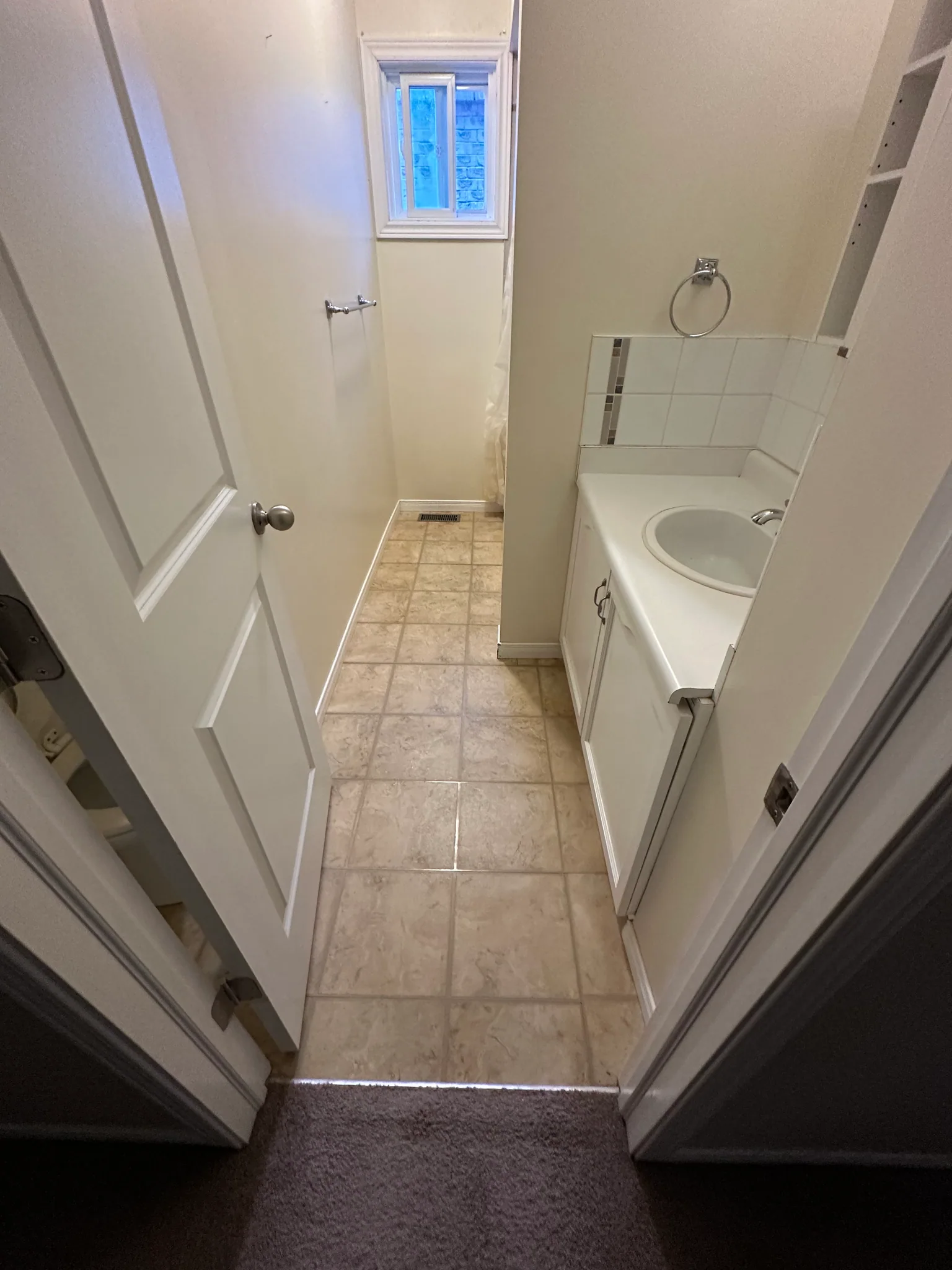 Tiled bathroom floor leading past a white vanity