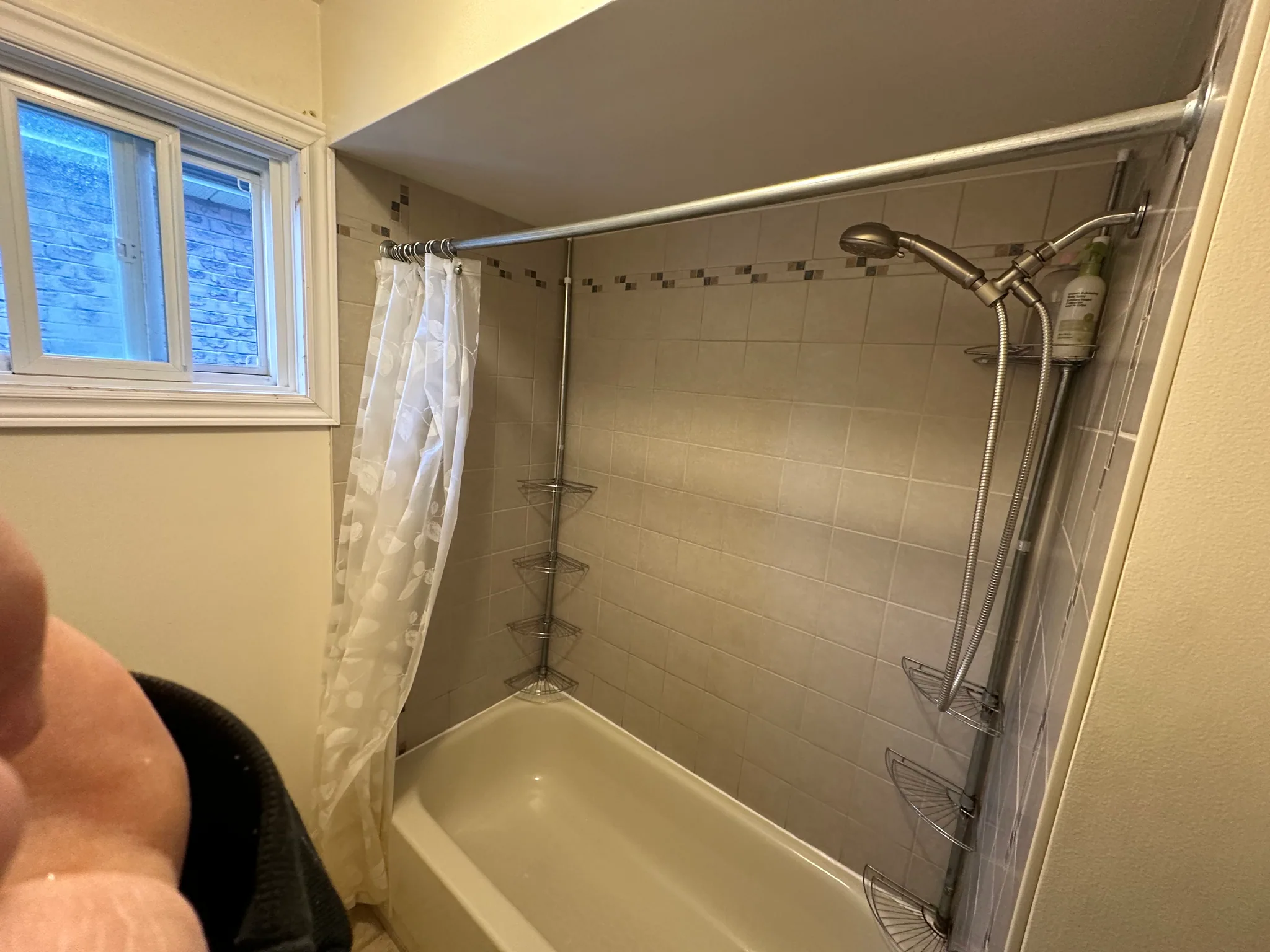 Tiled shower walls with a narrow mosaic border above the bathtub