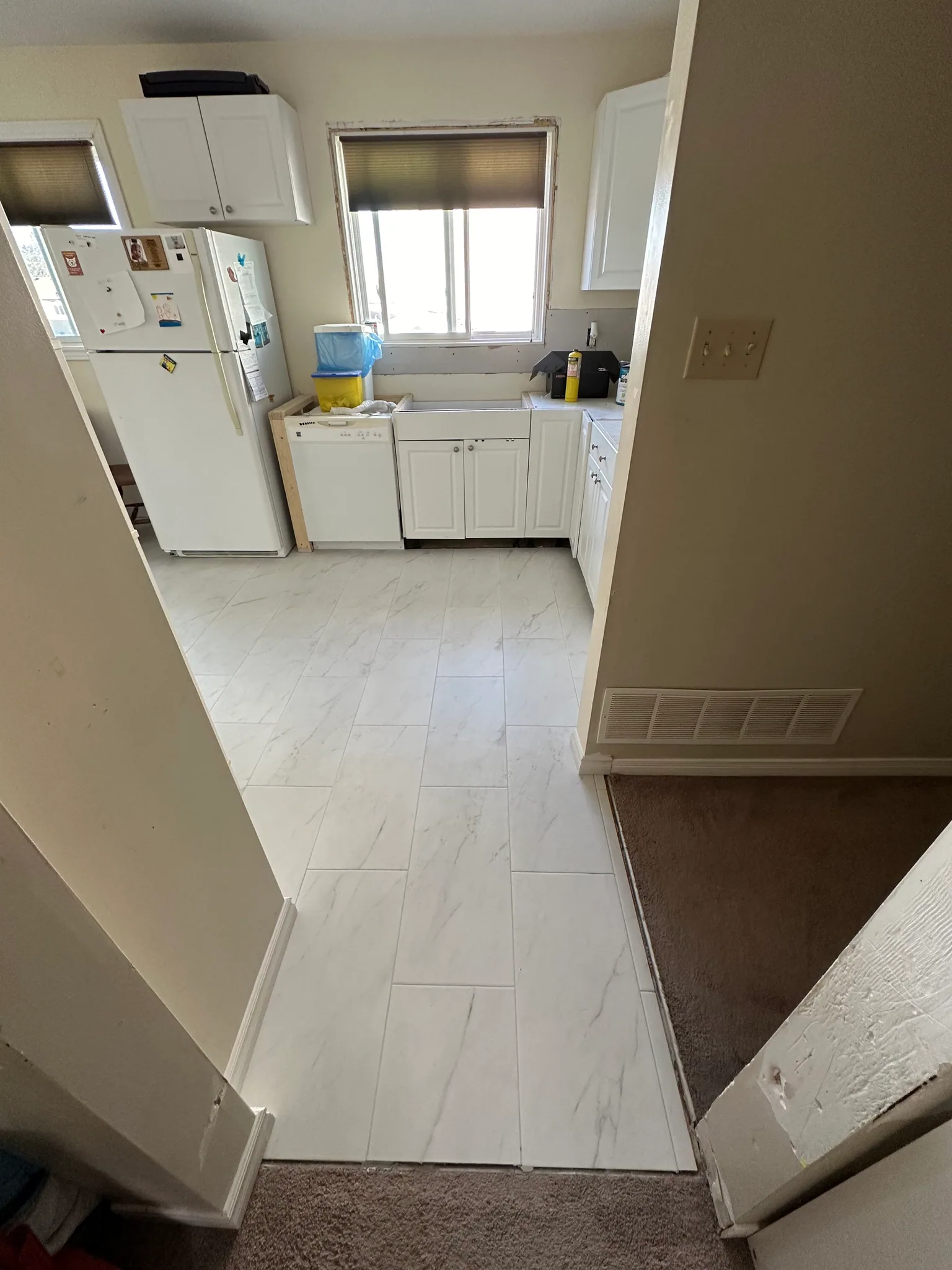 White kitchen floor tiles meeting the carpeted hallway