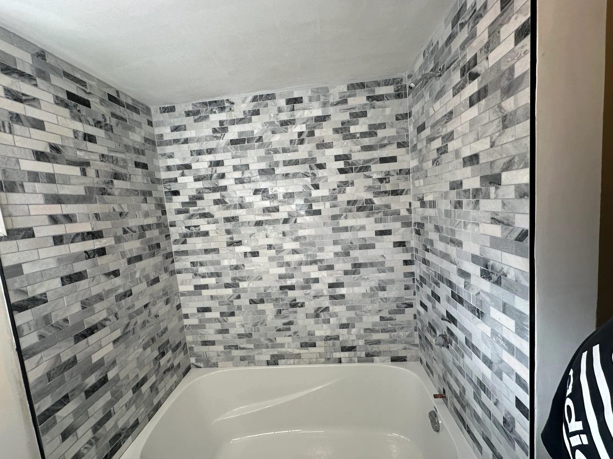 Grey and white wall tiles around a bathtub
