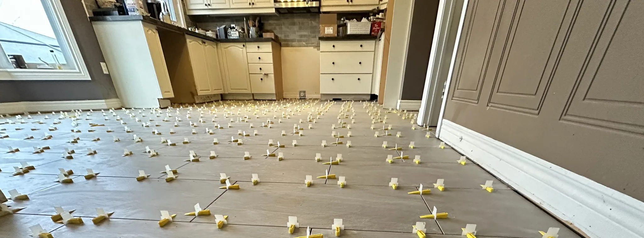 Kitchen floor tiles being installed with spacers